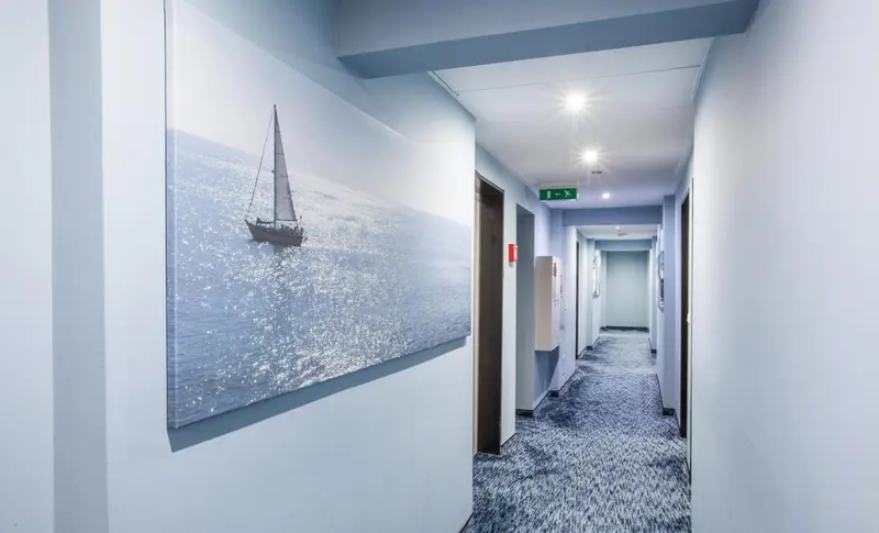 Couloir d'hôtel avec une décoration murale représentant un voilier sur l'eau.