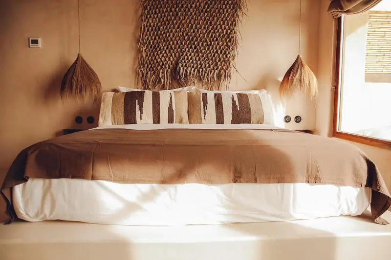 Un lit confortable est fait avec des textiles naturels et des oreillers décoratifs.