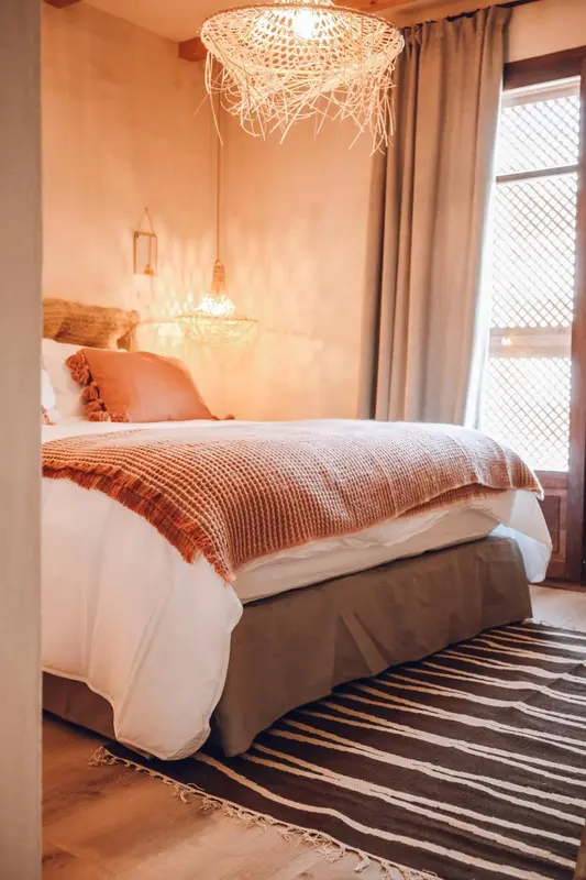 Une chambre à coucher lumineuse avec un lit recouvert d'une couverture texturée.