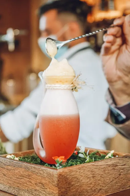 Un cocktail coloré est préparé avec une cuillère et servi dans un verre décoré.