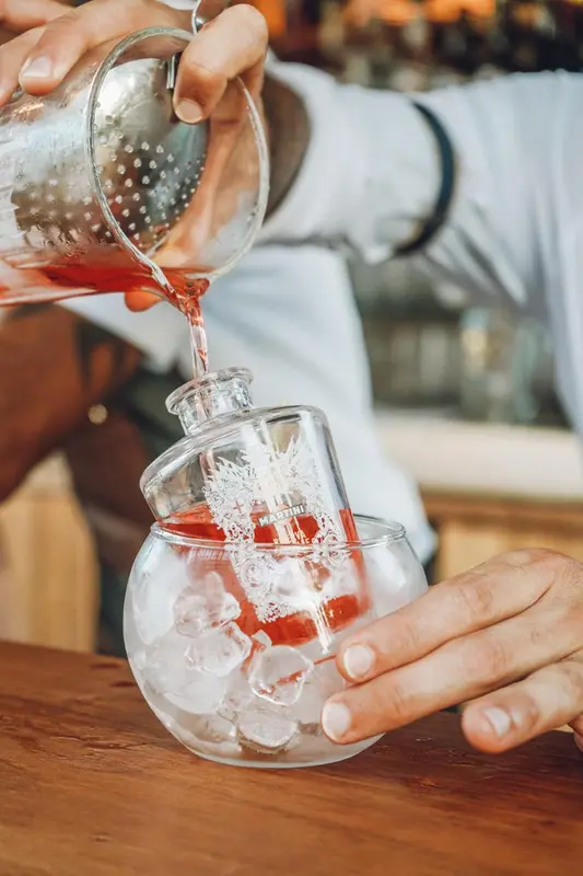 Un barman prépare un cocktail dans un verre à martini.