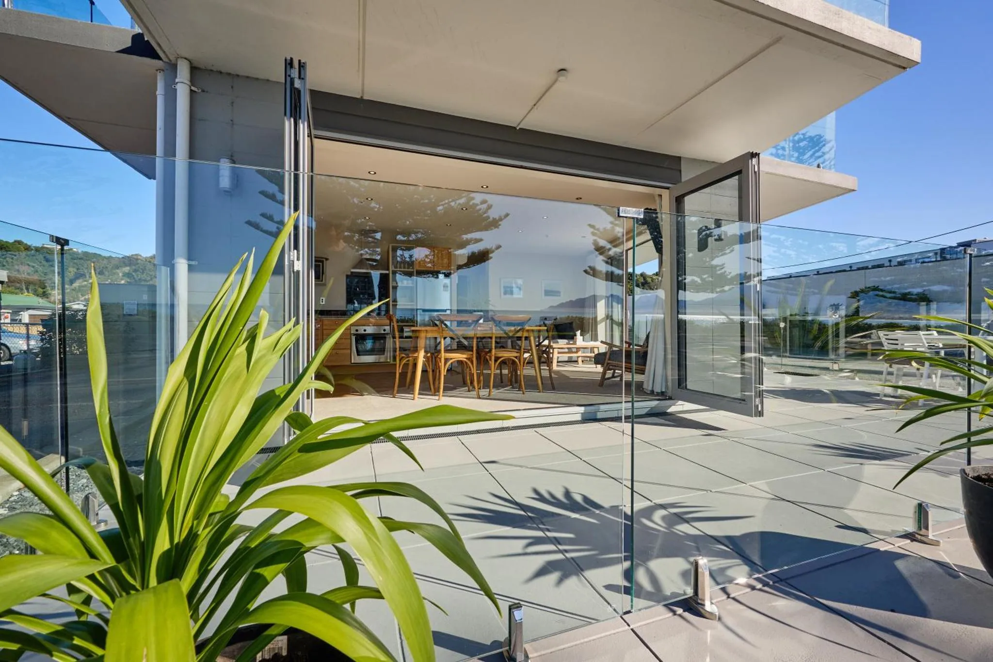 Une terrasse moderne s'ouvre sur une cuisine lumineuse avec vue sur la mer.