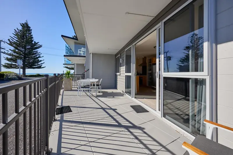 Terrasse ensoleillée donnant sur une cuisine et une vue sur la mer.