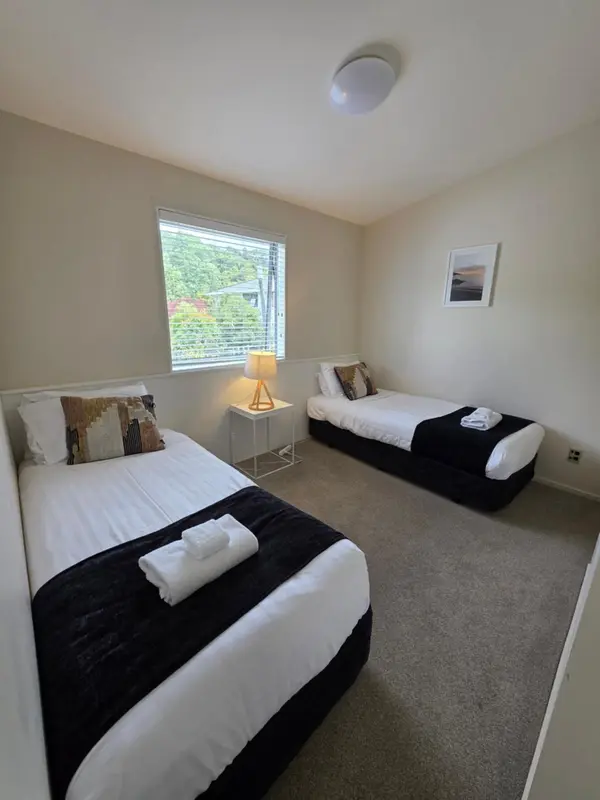 Une chambre lumineuse avec deux lits simples et une fenêtre.