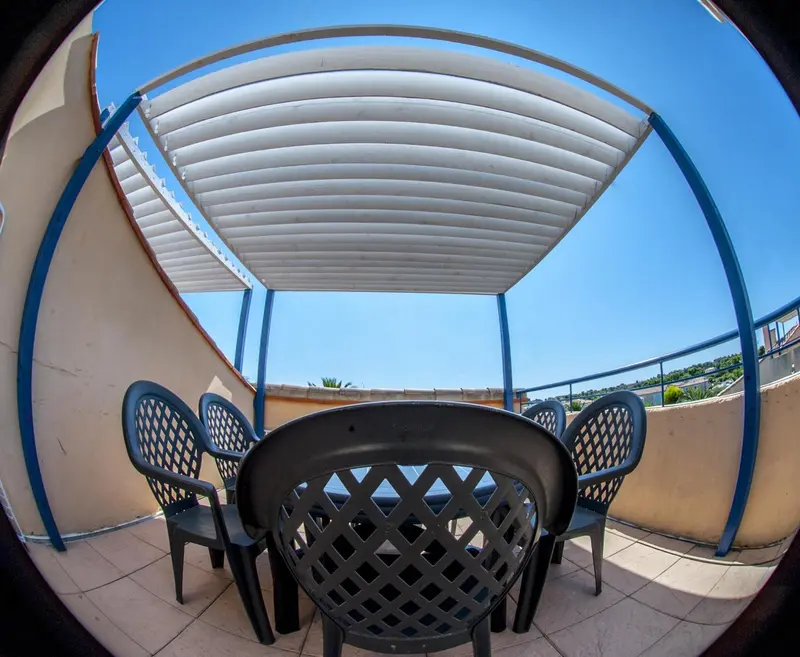 Terrasse ombragée avec mobilier de jardin noir.