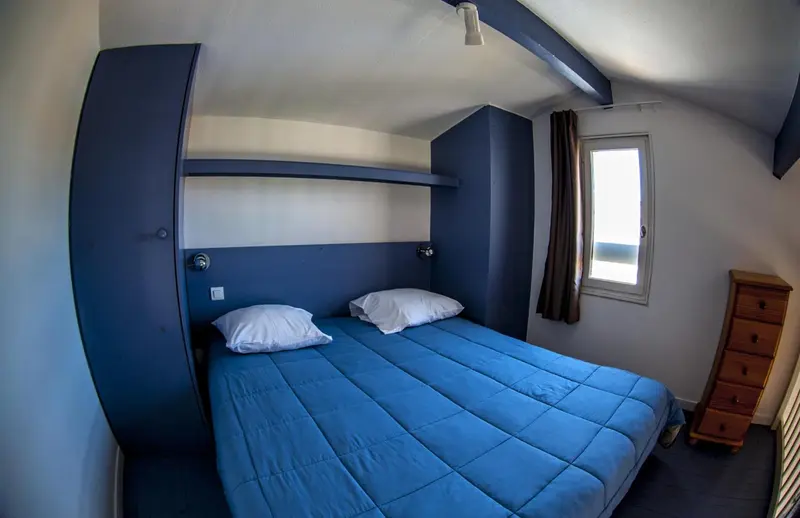 Une chambre avec un lit double et un meuble de rangement.