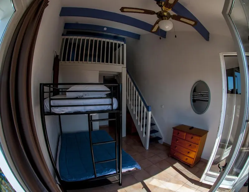 Une chambre avec des lits superposés et une commode en bois.