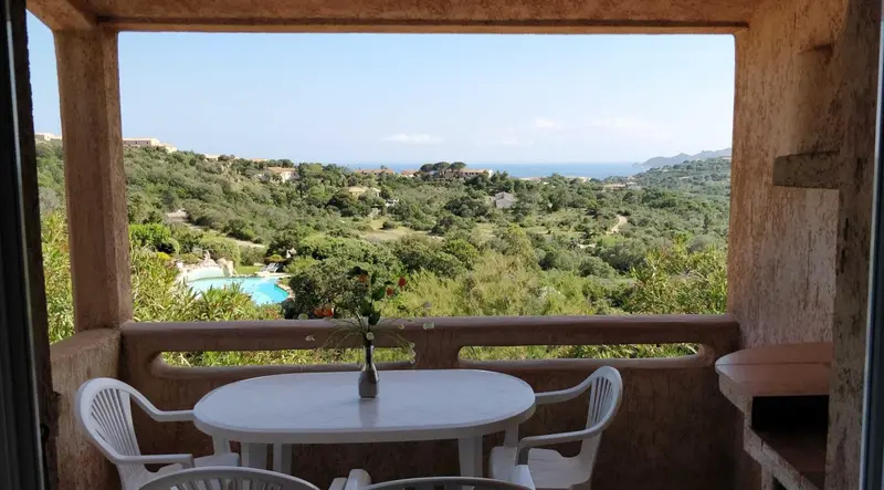 Vue d'un paysage verdoyant depuis une terrasse avec table et chaises.