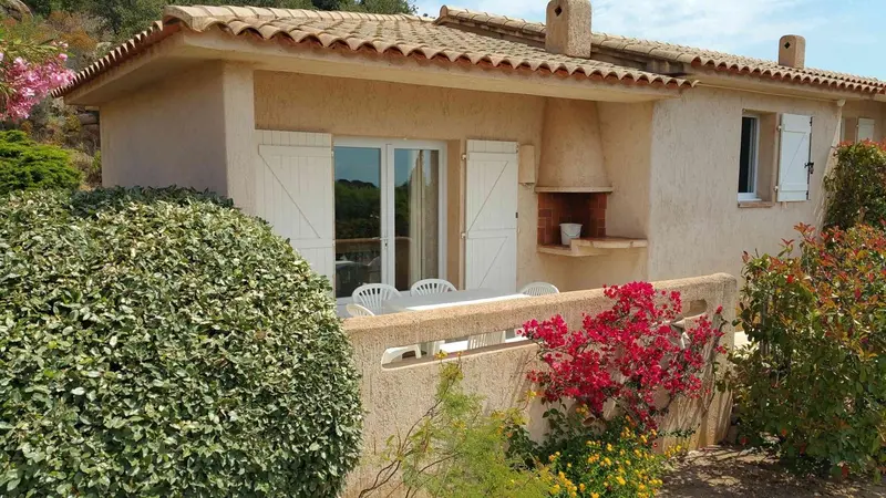 Façade d'une maison avec une terrasse fleurie et un coin repas.
