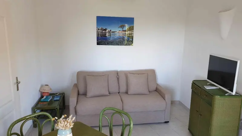 Un canapé beige et une table basse se trouvent dans une pièce lumineuse.