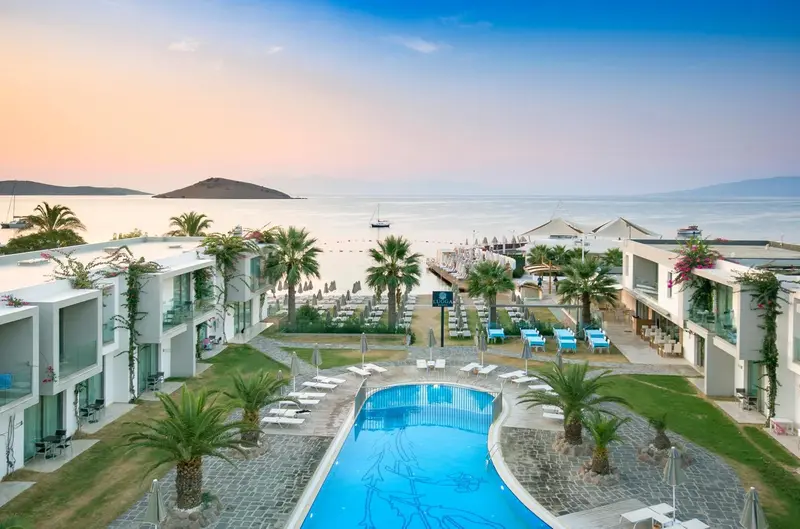 Vue aérienne d'un complexe hôtelier avec piscine et accès à la plage.