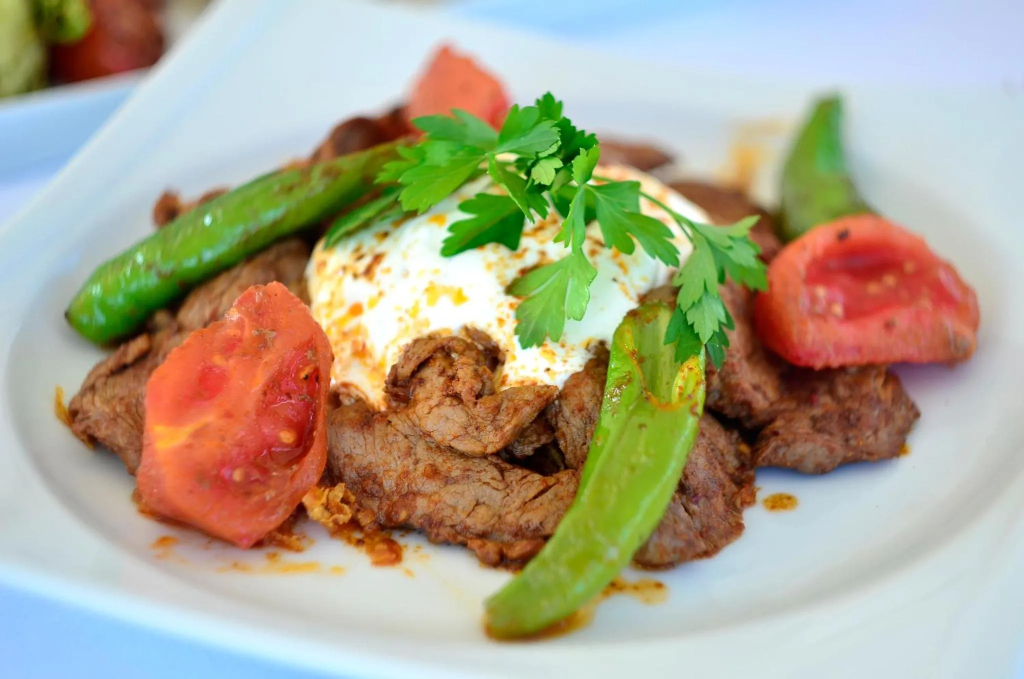 Assiette de viande grillée accompagnée de légumes frais et d'une sauce blanche.