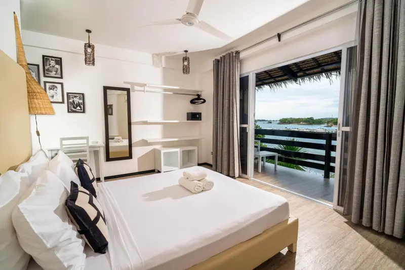 Chambre lumineuse avec un grand lit et une vue sur la mer.