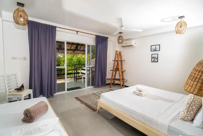 Une chambre lumineuse avec deux lits et un accès à une terrasse.