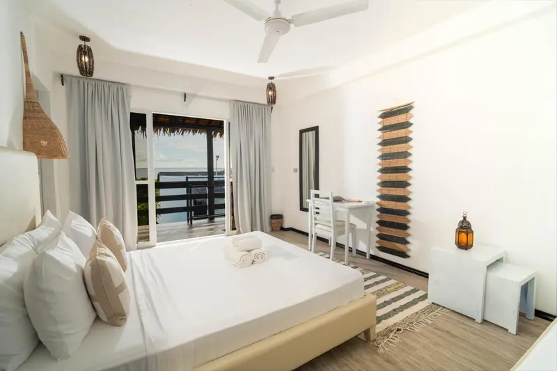 Une chambre lumineuse avec un grand lit et un accès à une terrasse.