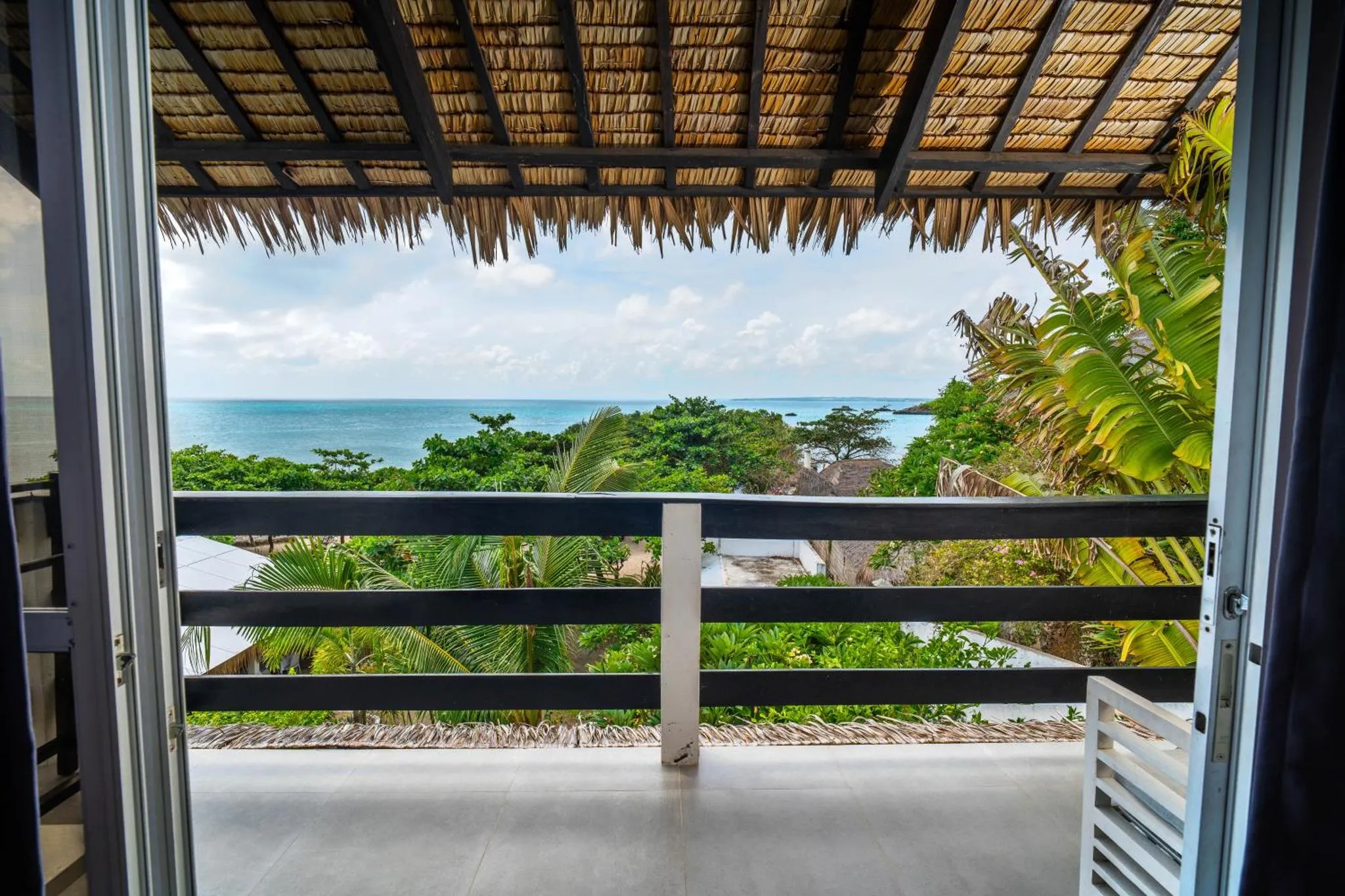 Vue sur la mer depuis une terrasse ombragée.