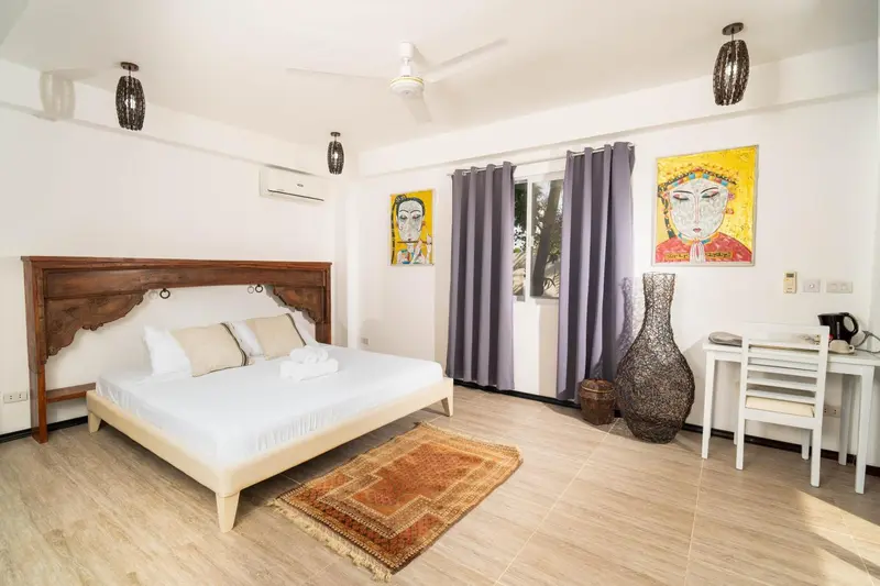 Une chambre lumineuse avec un grand lit et une décoration murale colorée.