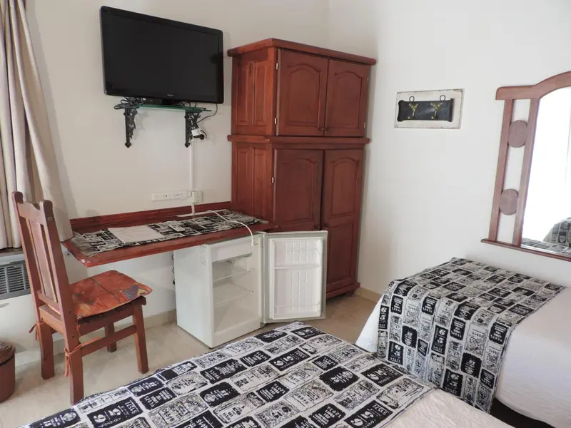 Une chambre lumineuse avec un bureau en bois et un lit recouvert d'une courtepointe à motifs.