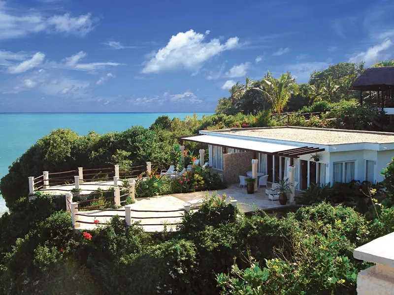 Vue d'un bâtiment blanc avec une terrasse surplombant la mer turquoise.