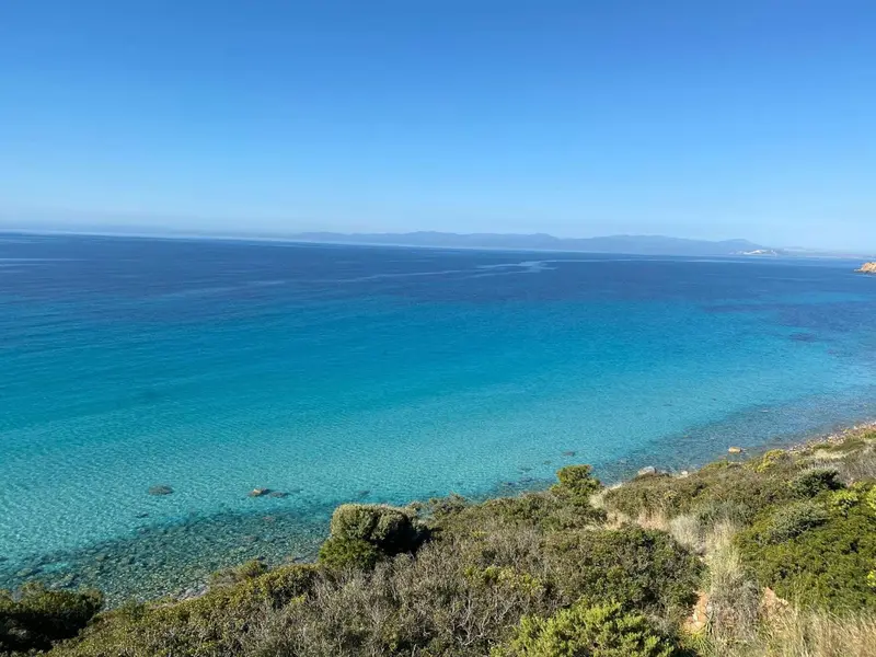 Vue aérienne d'une côte rocheuse et d'une mer turquoise sous un ciel bleu.