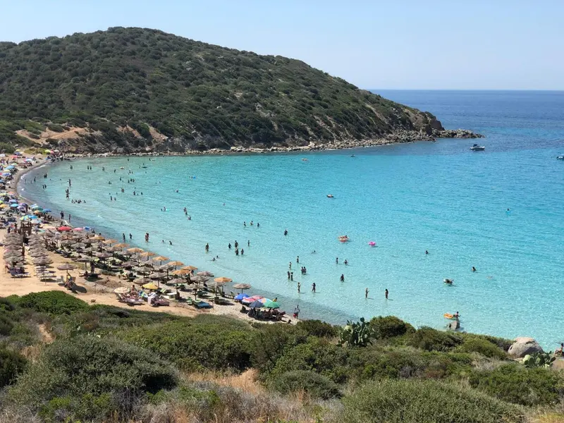 Une plage de sable fin bordée d'une eau turquoise et d'une végétation verdoyante.