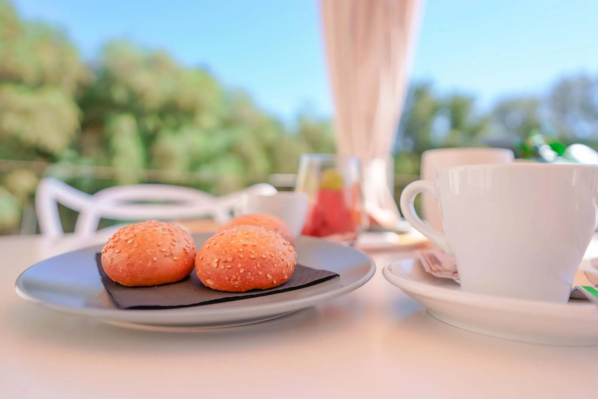 Une table blanche présente des viennoiseries et une tasse de café.