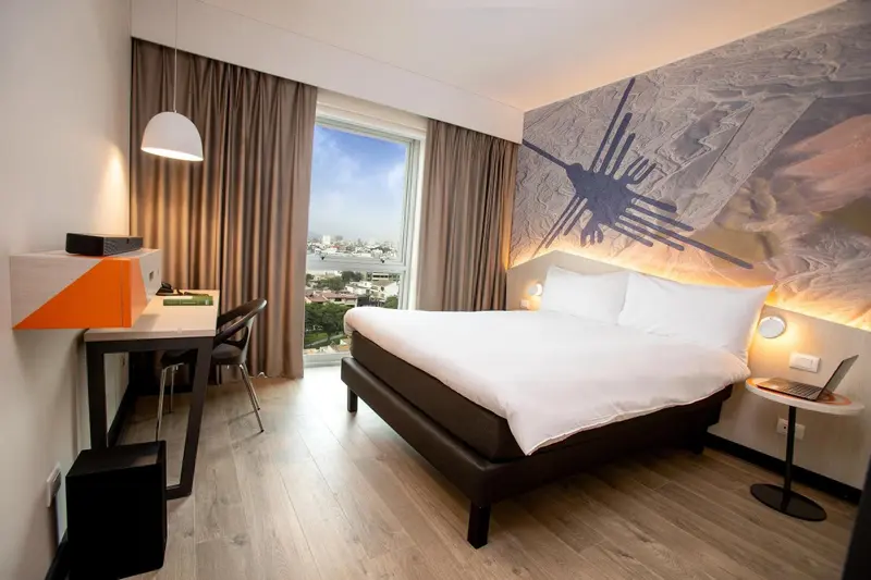 Une chambre d'hôtel moderne avec un grand lit et un bureau près d'une fenêtre.