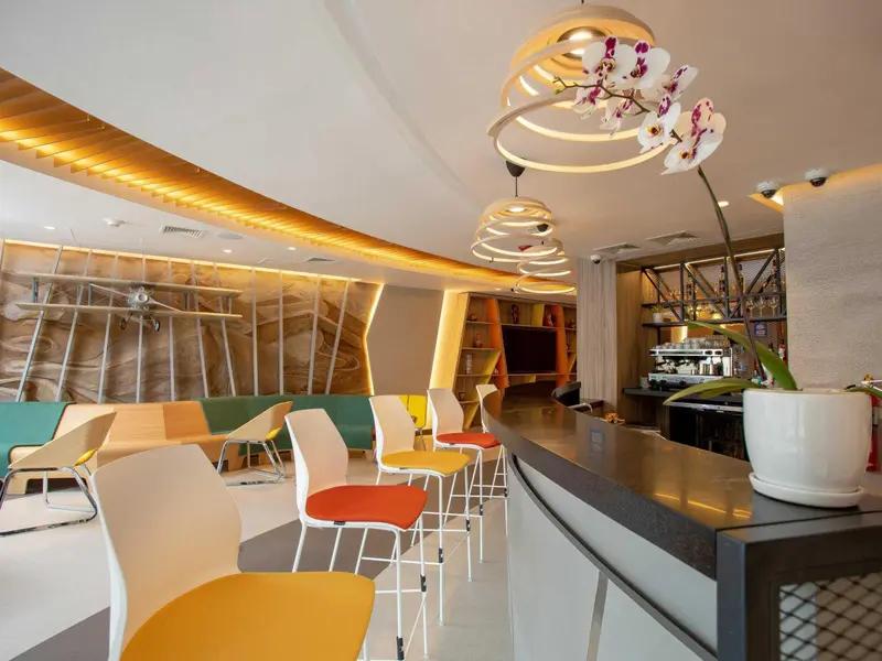 Une salle lumineuse avec des tables et des chaises colorées, un comptoir et des luminaires design.
