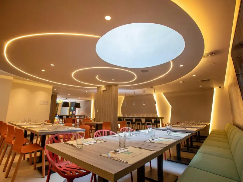 Une salle lumineuse avec des tables dressées pour un repas.
