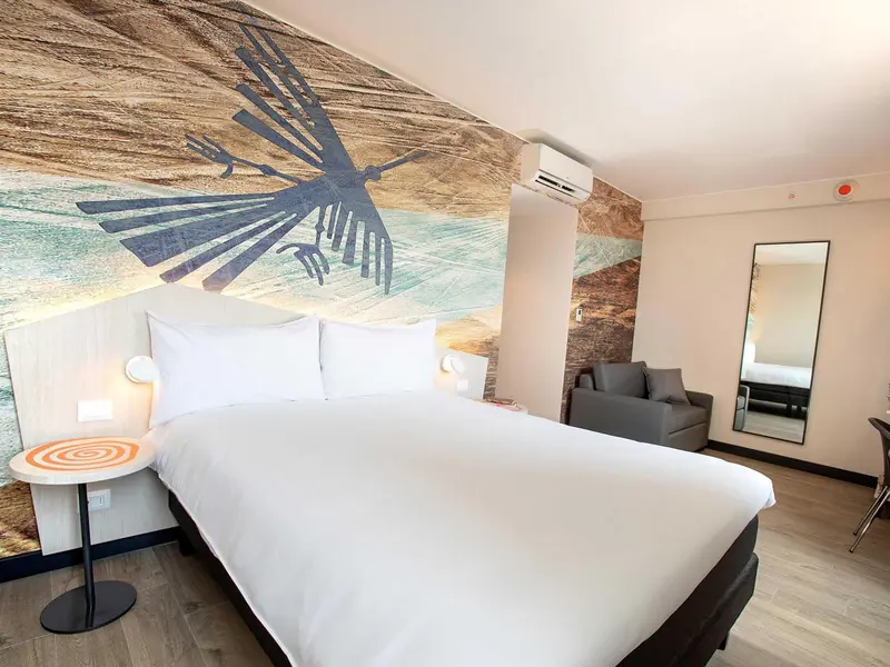 Une chambre lumineuse avec un grand lit et un mur décoratif.