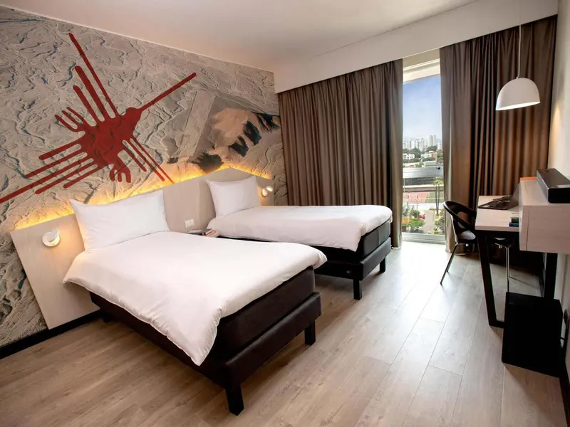 Chambre moderne avec deux lits simples et une décoration murale graphique.