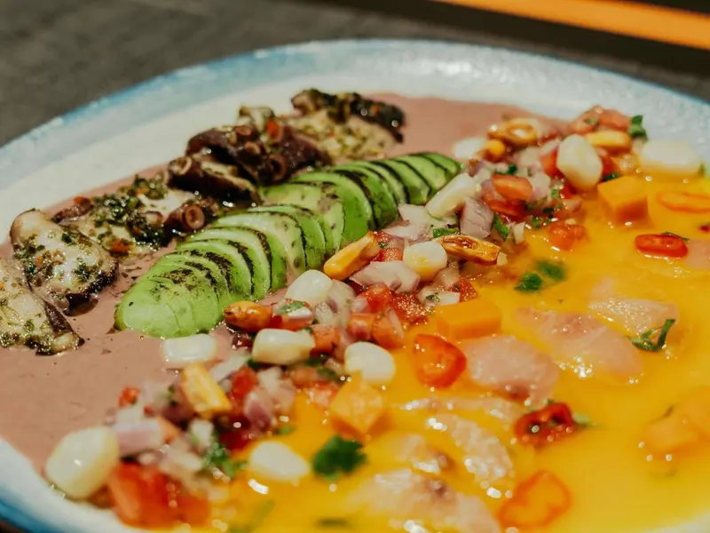 Assiette colorée avec des morceaux de poisson, d'avocat et de légumes.