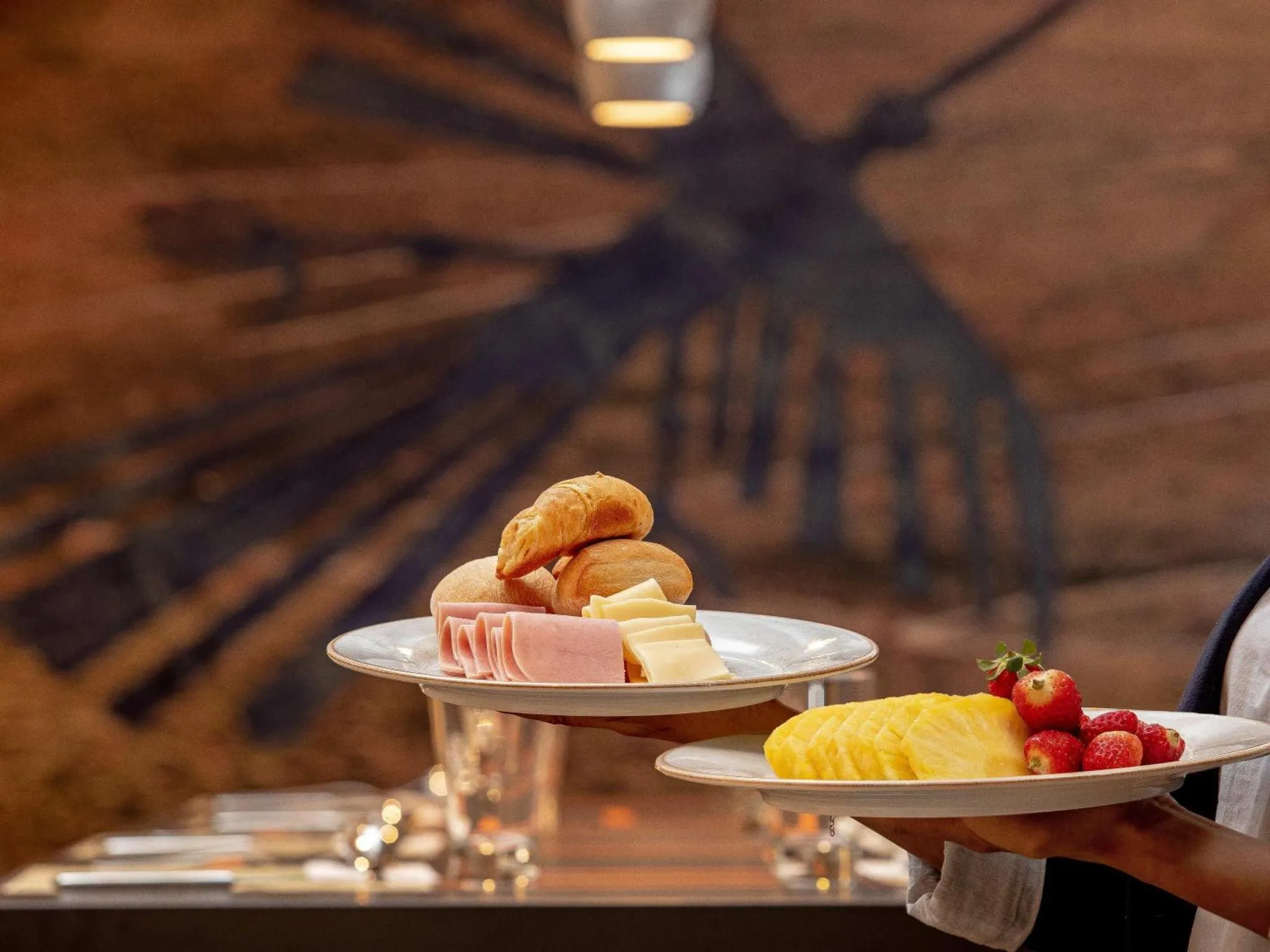 Assiette de viennoiseries et de fruits frais présentées sur une table.