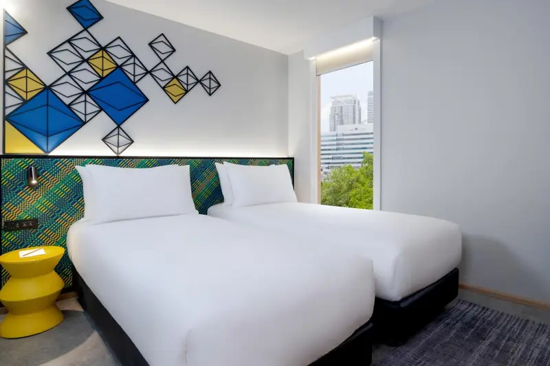 Une chambre lumineuse avec un lit double et une décoration murale graphique.
