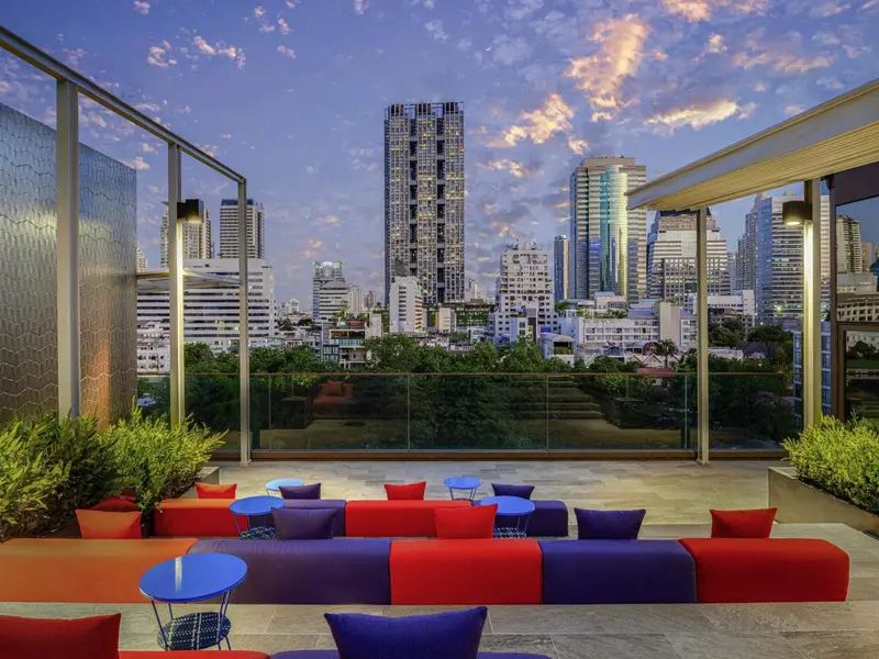 Terrasse aménagée avec des assises colorées et une vue sur la ville au coucher du soleil.