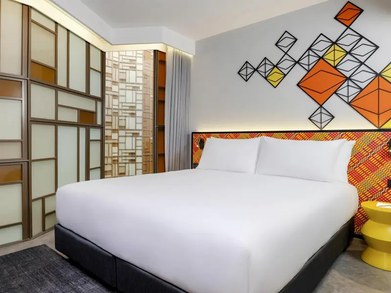 Une chambre moderne avec un grand lit recouvert d'une courtepointe colorée.