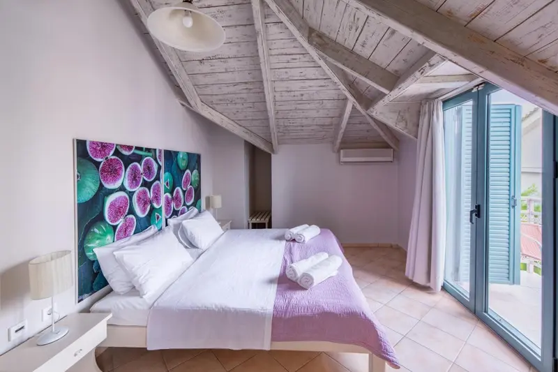Une chambre lumineuse avec un lit double et un accès à une terrasse.