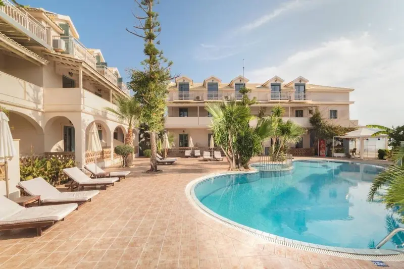 Bâtiment blanc à plusieurs étages avec des transats et une piscine au premier plan.