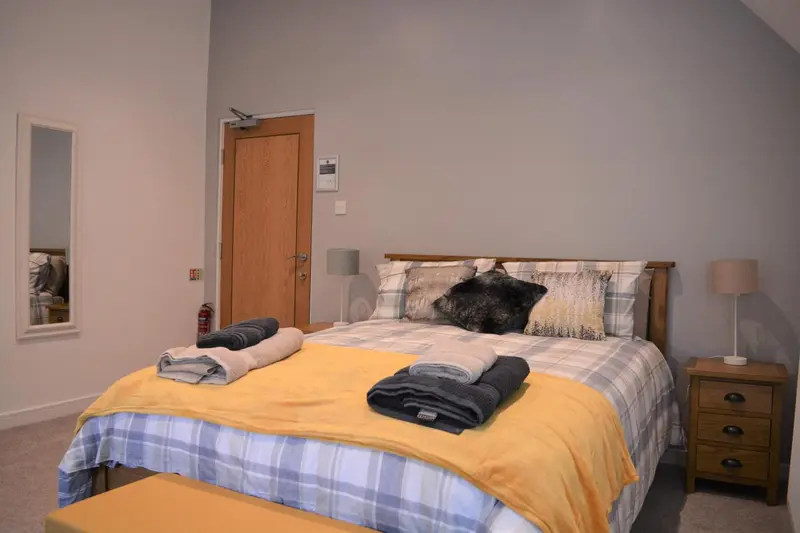 Une chambre lumineuse avec un grand lit recouvert d'une courtepointe colorée.