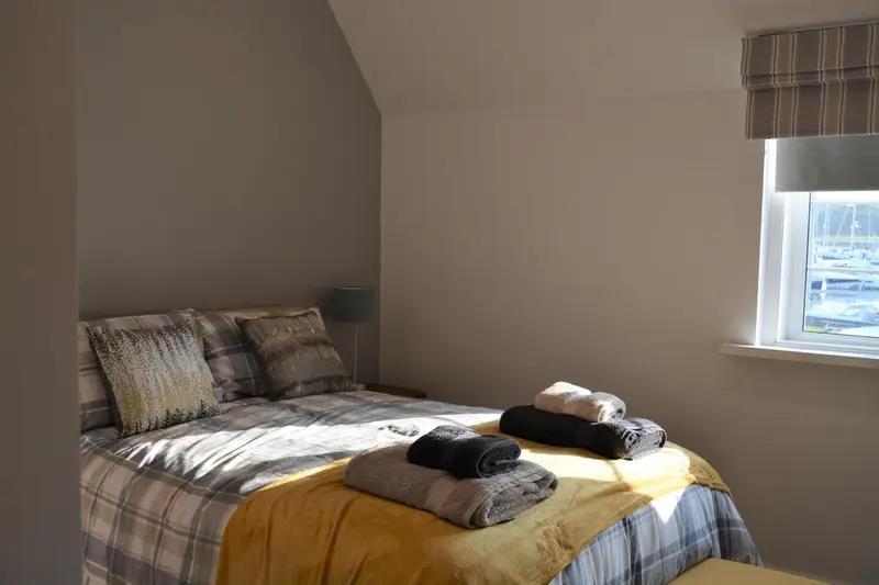 Une chambre lumineuse avec un lit recouvert de plaids et d'oreillers.