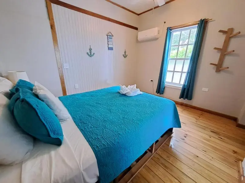Une chambre lumineuse avec un grand lit recouvert d'une courtepointe turquoise.