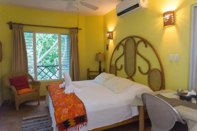 Une chambre lumineuse avec un lit recouvert d'un couvre-lit orange et blanc.