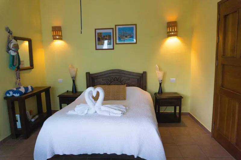 Une chambre lumineuse avec un lit décoré de serviettes en forme de cygnes.