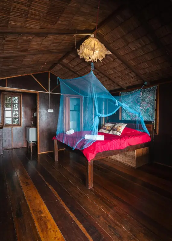 Une chambre à coucher avec un lit à baldaquin et un sol en bois sombre.