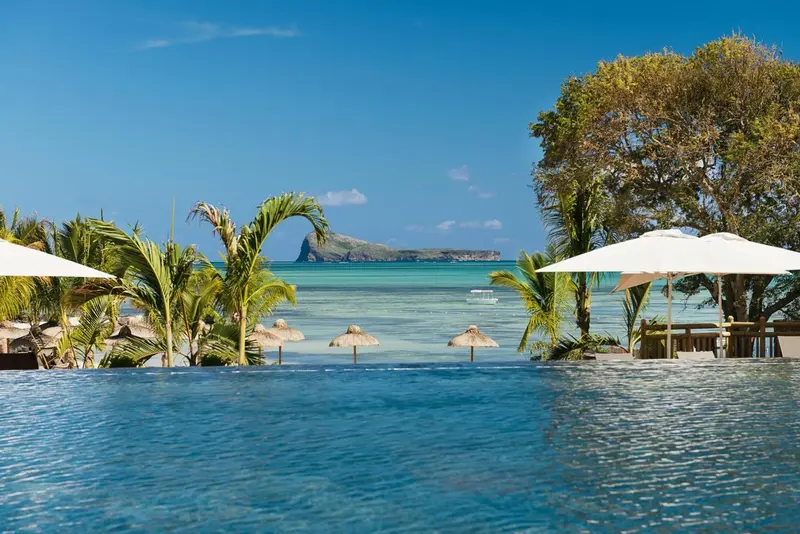 Vue sur une piscine à débordement donnant sur une plage et l'océan.