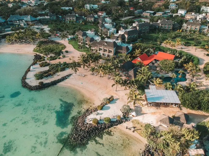 Vue aérienne d'un complexe hôtelier bordant une plage de sable blanc et une eau turquoise.