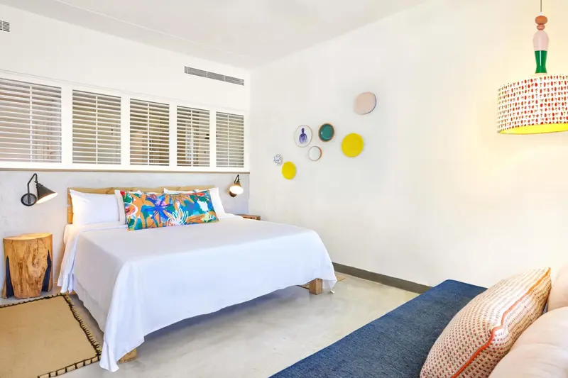 Une chambre lumineuse avec un grand lit recouvert de blanc.