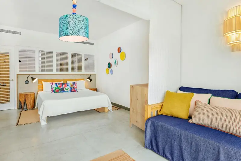Une chambre lumineuse avec un grand lit et un coin salon.
