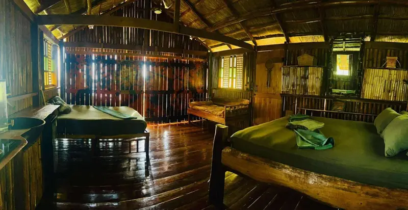 Intérieur d'une chambre avec deux lits et un coin salon en bois.