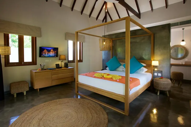 Une chambre lumineuse avec un lit à baldaquin et une décoration tropicale.